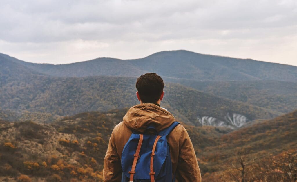 A man with a hiking backpack on looking out to a vast dry landscape