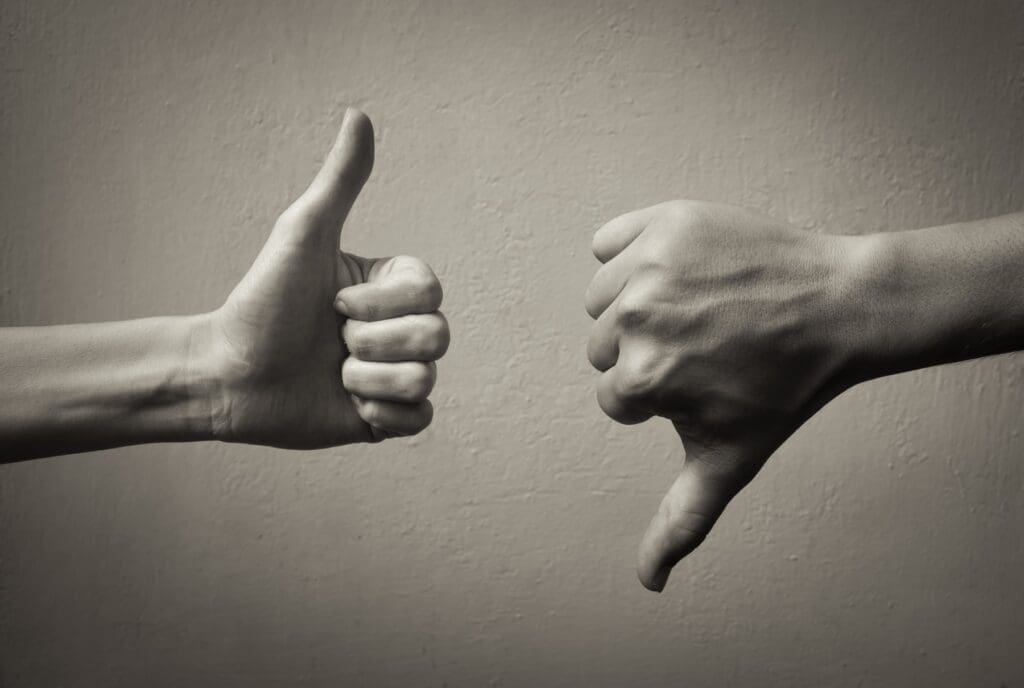 Two hands one showing thumbs up one showing thumbs down